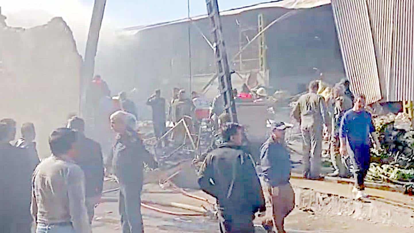 حادثہ کی جگہ پر لوگ اور امدادی عملہ مصروف، تباہ شدہ عمارت اور ملبہ.