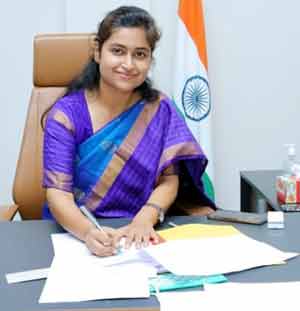 ہندوستانی خاتون افسر کی تصویر، جو دفتر میں کام کر رہی ہے، بھارتی پرچم کے سامنے بیٹھی ہے۔.