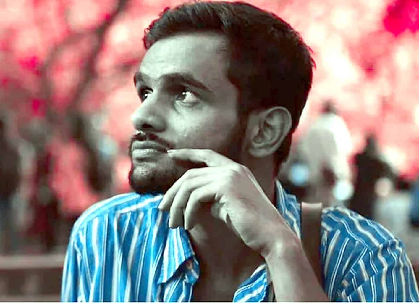 فکر مند شخص کی تصویر، بیرونی ماحول میں، گہرے خیالات میں مبتلا، سرخ پھولوں کے پس منظر کے ساتھ.