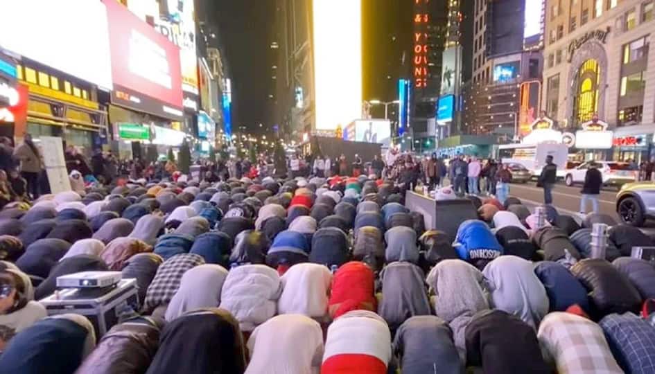 مصلّی میں نماز پڑھتے ہوئے افراد، شہر کی روشنیاں اور روشنیوں سے بھرپور، مذہبی اور روحانی اجتماع کی تص.