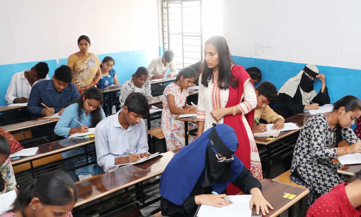 تعلیمی امتحان دیتے ہوئے طلبہ، خواتین اور مرد، کلاس روم میں.