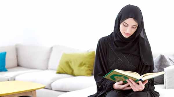 خاتون مسلمہ کتاب پڑھتی ہوئی، آرام دہ گھر کے ماحول میں.