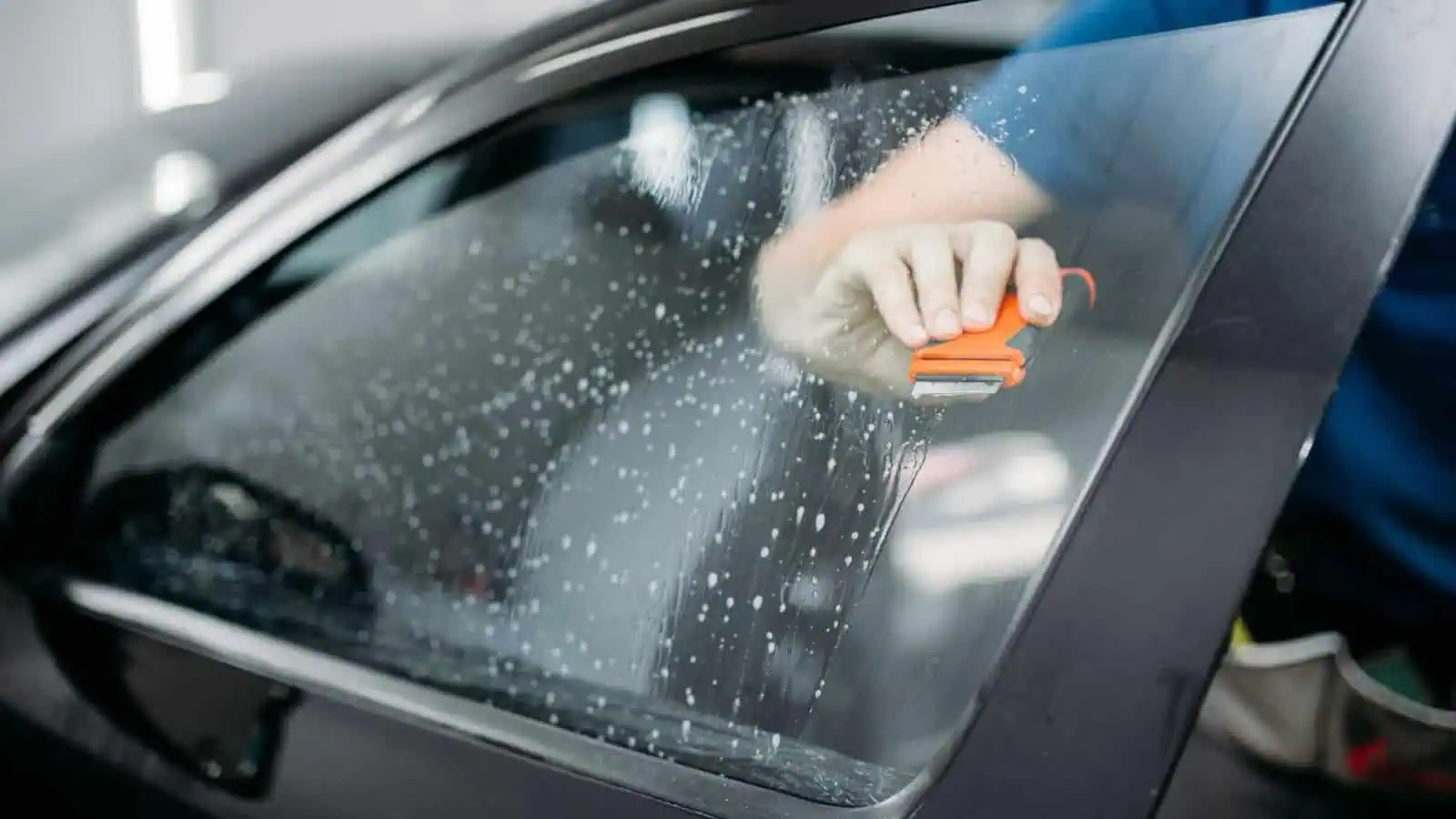 کار واش کرتے ہوئے کار کا شیشہ صاف کر رہا ہے.