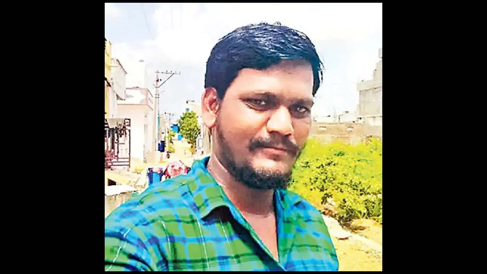 خود ساختہ تصویر میں ایک نوجوان مرد، سبز اور نیلے چیکڈ شرٹ میں، کھلے میدان میں، روشن دن کے دوران، مسک.