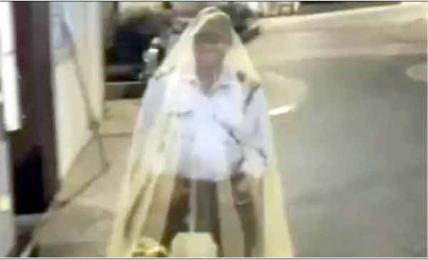 سڑک پر چلنے والا شخص، لباس میں سفید اور ہلکی چادر کے ساتھ.