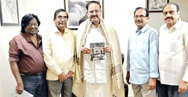 تصویری گروپ میں پانچ مرد اور خواتین افراد، ایک شخص ہینڈ میں اخبار لیے ہوئے.