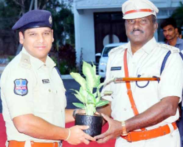 پولیس اہلکار ایک دوسرے کو پودا دے رہے ہیں، فلاحی سرگرمی کی تصویر.