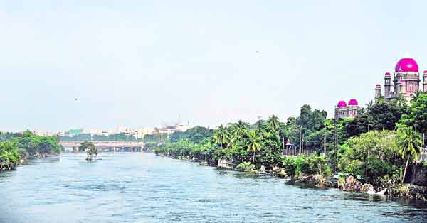 سندھ کے کنارے دریائے سندھ کا پرسکون منظر، سرسبز درخت اور عمارتیں.