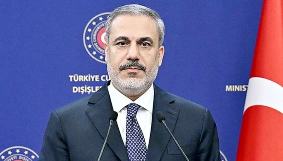 ترکیہ کے وزیر خارجہ کی تصویر، وہ ایک پریس کانفرنس میں، پس منظر میں ترکی کا جھنڈا اور وزارت خارجہ کا.