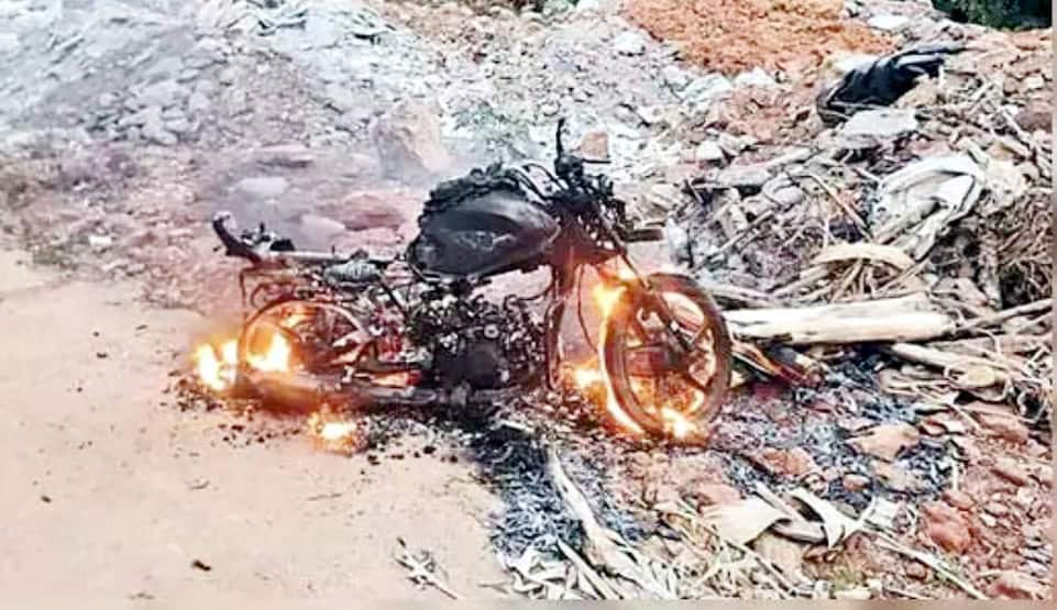 آگ لگتی ہوئی موٹر سائیکل، حادثہ کے بعد، سڑک کے کنارے، سیاہ دھواں اور چنگاریاں.