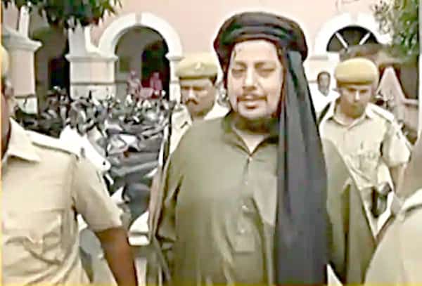 پولیس اہلکاروں کے ساتھ ایک شخص، ممکنہ طور پر سیاسی رہنم.