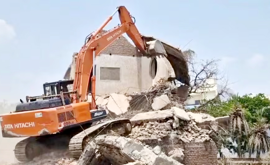 تباہ شدہ عمارت کی تصویر، ایکسکیویٹر عمارت کو مسمار کر رہا ہے.