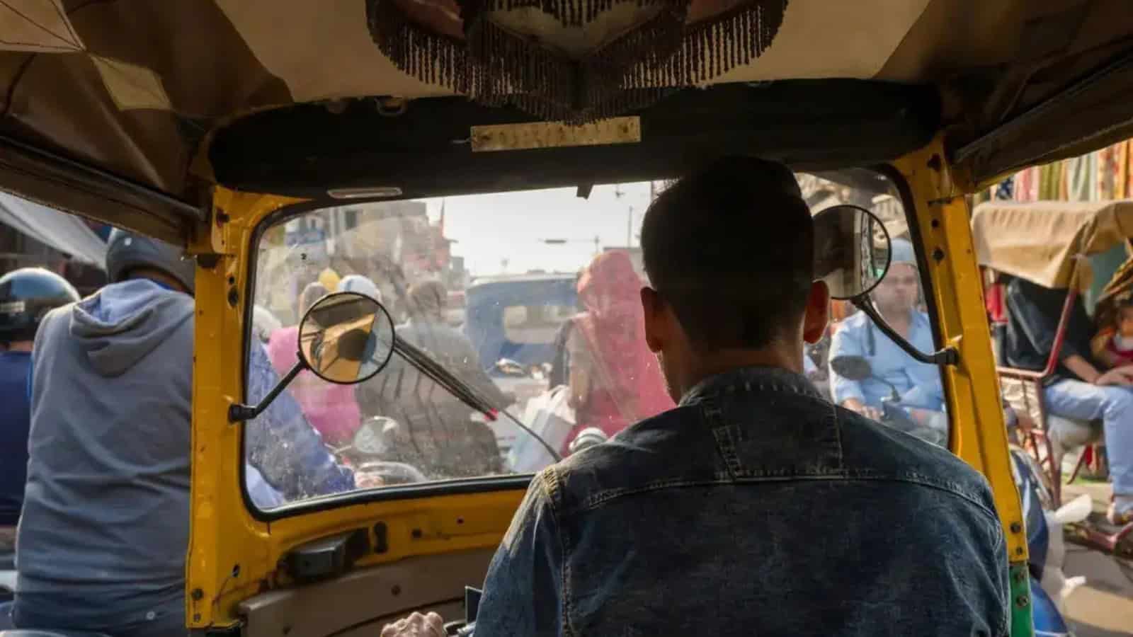 پہلو سے دیکھتے ہوئے ایک شخص رکشہ کے اندر بیٹھا ہوا.