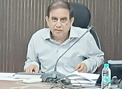 سیاستدان دفتر میں بیٹھا، میز پر کاغذات اور پانی کی بوتل کے ساتھ.