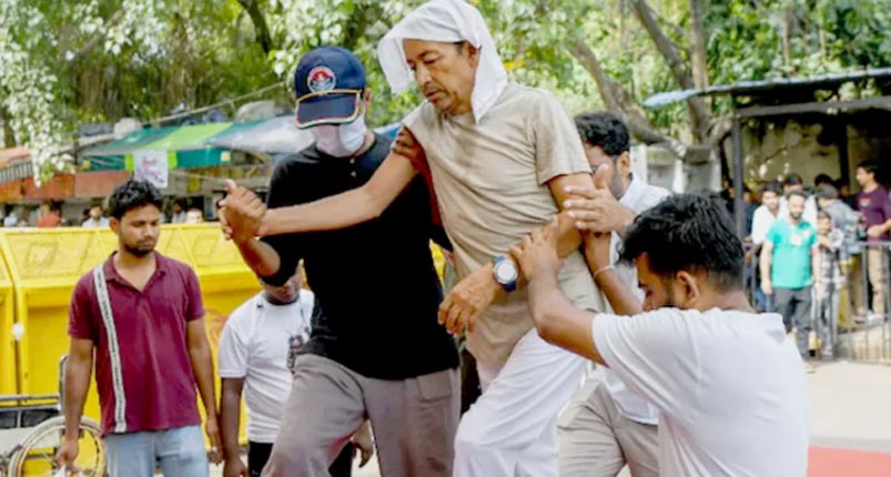 ہجوم میں ایک شخص دوسرے کو دھکا دے رہا ہے، لوگ دیکھ رہے ہیں.