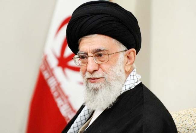 ایرانی رہنما، روایتی لباس میں، سر پر ٹوپی، مسکراہٹ کے ساتھ.