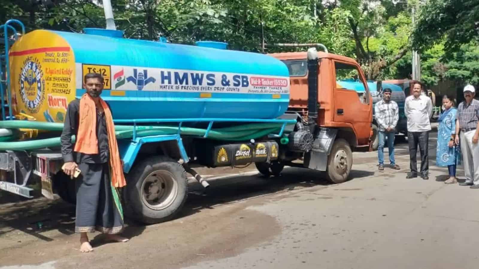 پانی کا ٹینکر اور چند لوگ سڑک پر کھڑے ہیں.