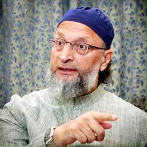 سیاستدان گفتگو کرتے ہوئے، سر پر ٹوپی اور چشمہ پہنے ہوئے.