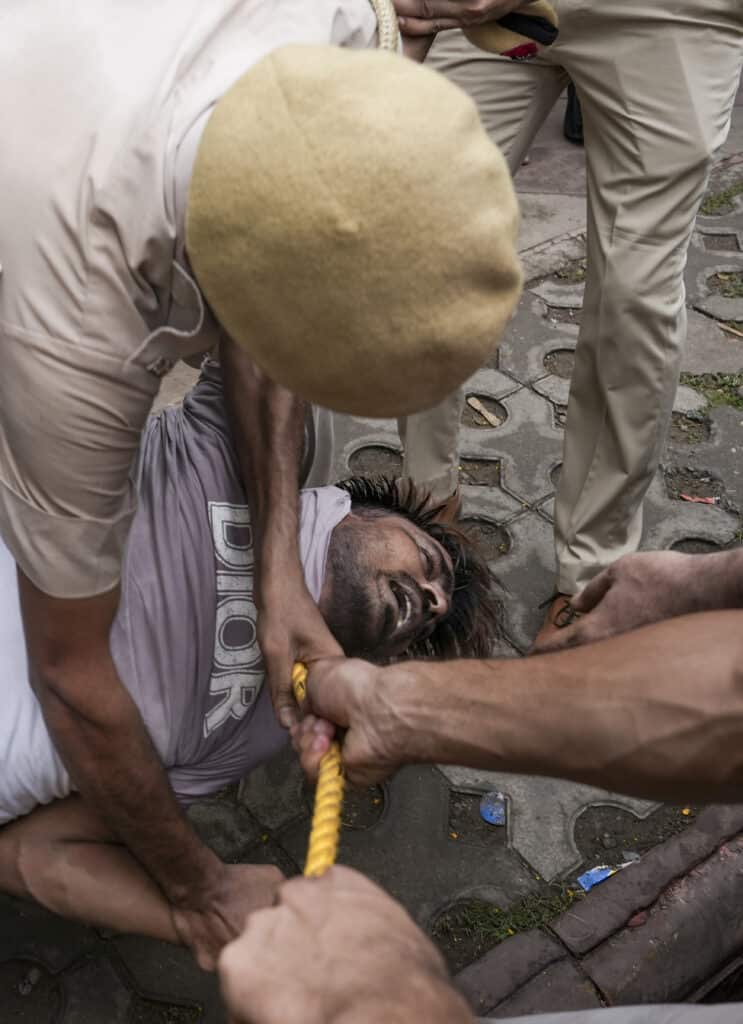 پولیس اہلکار ایک شخص کو گرفتار کر رہا ہے.