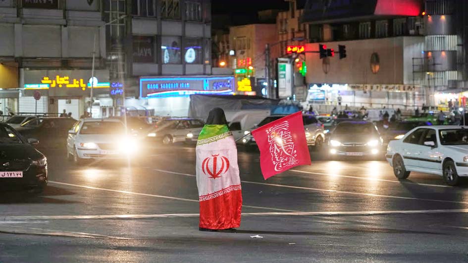 شخص ایرانی اور سعودی پرچم کے ساتھ سڑک پر کھڑا ہے.