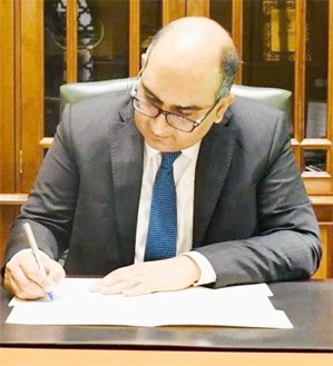 آدمی دفتر میں بیٹھا، قلم سے لکھ رہا ہے، بزنس یا سرکاری کام.