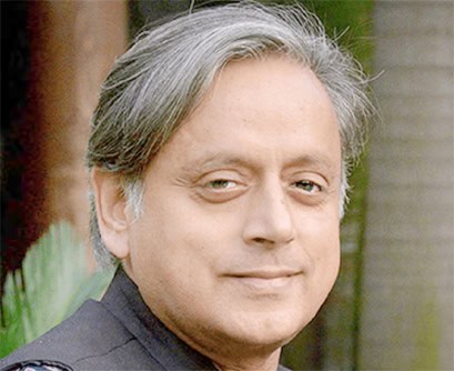 پہلو سے مسکراتے ہوئے شخص کی تصویر، پس منظر میں سبز پودے.