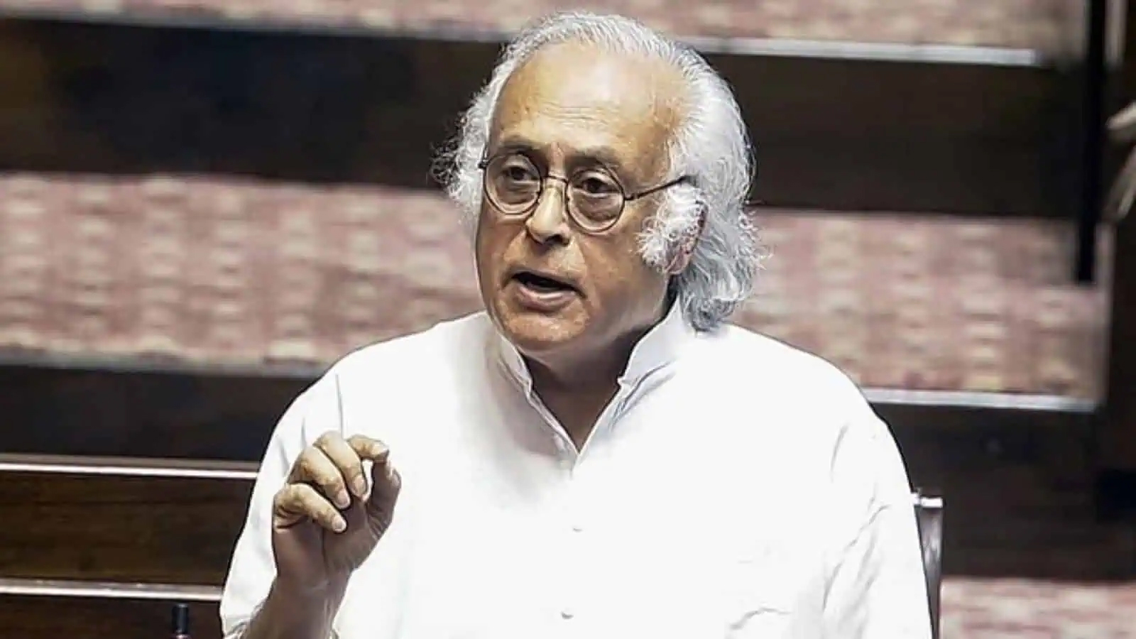 سیاستدان گفتگو کرتے ہوئے، سفید بالوں اور عینک کے ساتھ.