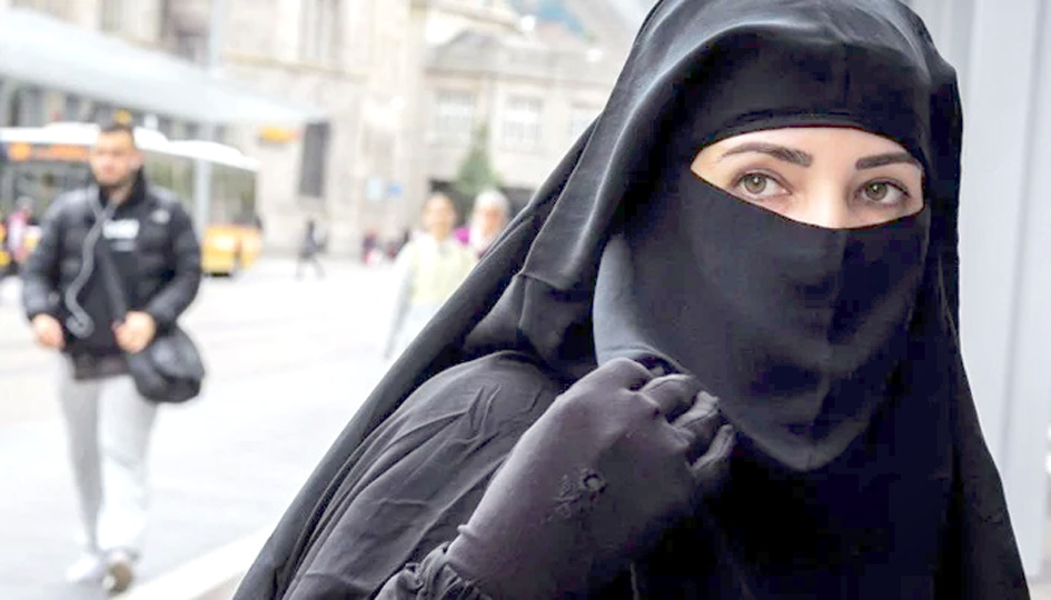 عورت کا نقاب پہنے ہوئے، شہر کی سڑک پر، شہری پس منظر کے ساتھ.