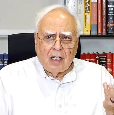 سیاستدان کی تصویر، وہ گفتگو کر رہے ہیں، کتابوں کے ساتھ پس منظر میں.