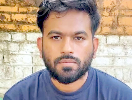 نوجوان مرد کی تصویر، گہرے بال اور داڑھی کے ساتھ، پس منظر میں اینٹوں کی دیوار.