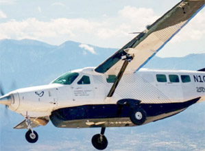 ہوائی جہاز بلند پہاڑوں کے پس منظر میں پرواز کرتا ہوا.