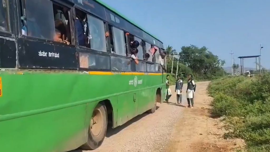 بہادر لڑکی رکھی ہوئی ایس آر ٹی سی بس کے سامنے کھڑی ہے.