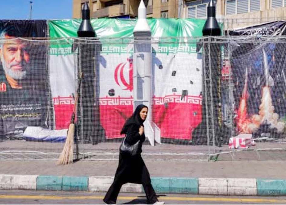 خاتون سڑک پر چلتی ہوئی، ایران اور عراق کے پرچم کے سامنے.