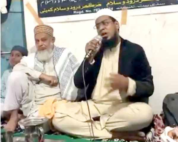 مذہبی رہنما تقریر کر رہے ہیں، دیگر افراد بھی موجود ہیں.