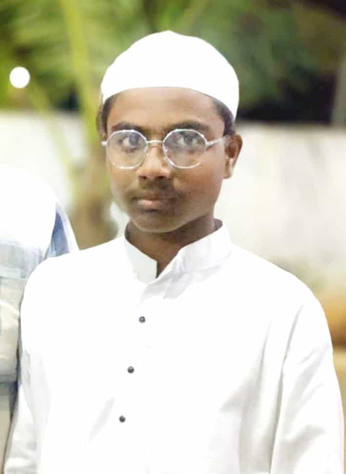 نوجوان مسلم طالب علم، سفید لباس اور ٹوپی میں، گہرے نظریں اور عزم کے ساتھ.
