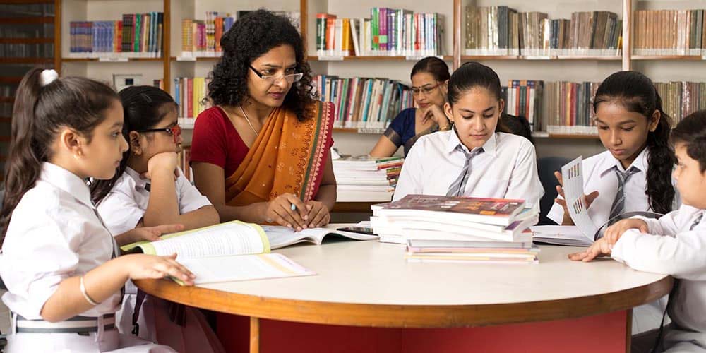 اساتذہ اور طالبات کتابوں کے ساتھ تعلیمی نشست میں مصروف.