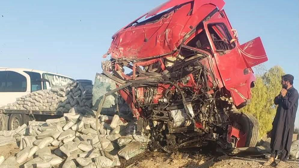 تباہ شدہ سرخ ٹرک اور حادثہ کی جگہ کی تصویر.
